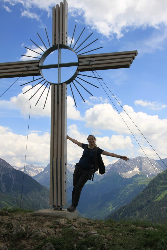 Das Bild zeigt die Fotografin bei einem Gipfelkreuz